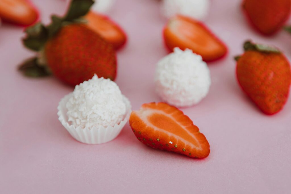 pexels-photo-6534608-6534608 Delicious strawberries and coconut truffles on a pink background, perfect for dessert inspiration.